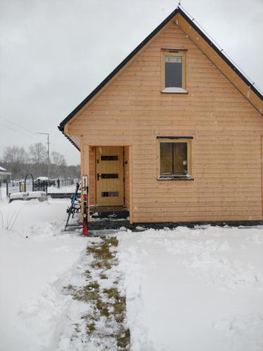 a wooden building with a door in the snow at Winnica Zatorska in Olszyny