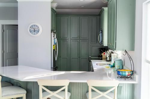 a kitchen with green cabinets and white countertops at Blue Haven - 1414 Oleander in Dauphin Island
