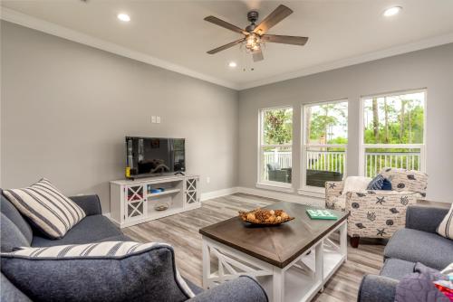 a living room with two couches and a tv at Blue Haven - 1414 Oleander in Dauphin Island
