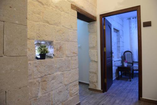 a hallway with a stone wall and a door at Mensa Christi Guesthouse in Nazareth