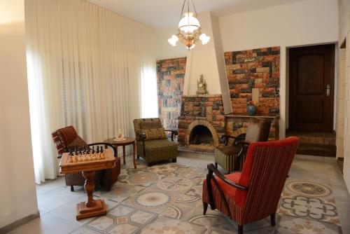 a living room with chairs and a fireplace with a chessboard at Mensa Christi Guesthouse in Nazareth