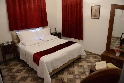 a bedroom with a large bed with red curtains at Mensa Christi Guesthouse in Nazareth