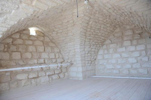 an attic with a stone wall and a wooden floor at Mensa Christi Guesthouse in Nazareth