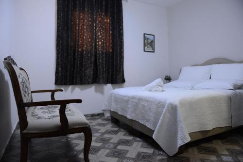 a bedroom with a bed and a chair and a window at Mensa Christi Guesthouse in Nazareth