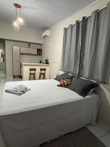 a bedroom with a large white bed with grey curtains at Chalé da Ana in Tutóia