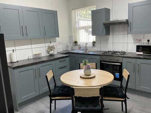 a kitchen with a wooden table with chairs and a tableasteryasteryasteryasteryastery at Homely Whittier Terrace 3 Bedroom House in Nottingham