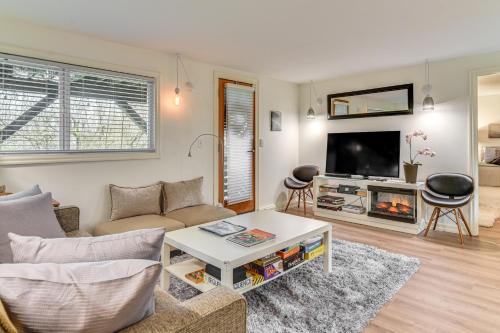 a living room with a couch and a tv at 3 Mi to Downtown Portland Lush Flat with Fire Pit in Portland