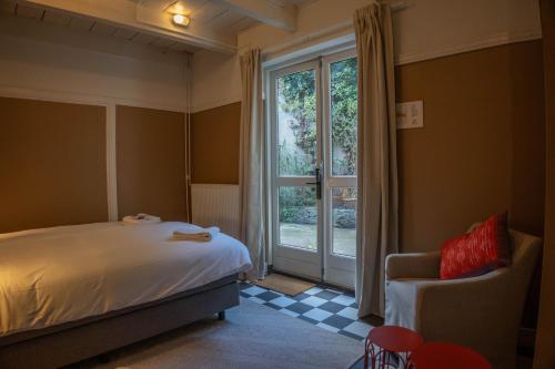 a bedroom with a bed and a window and a chair at The Guesthouse in Gouda