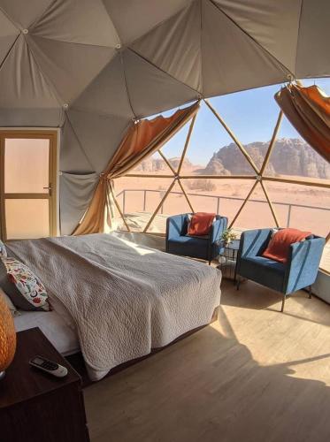 a bedroom with a bed and two chairs in a tent at WADl RUM DESERT CAMP in Wadi Rum