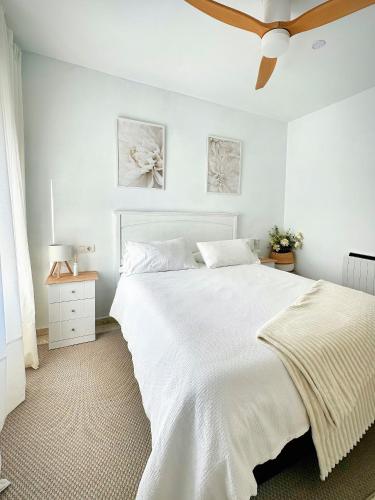 a bedroom with a large white bed and a ceiling fan at Limon Home in Benacazón