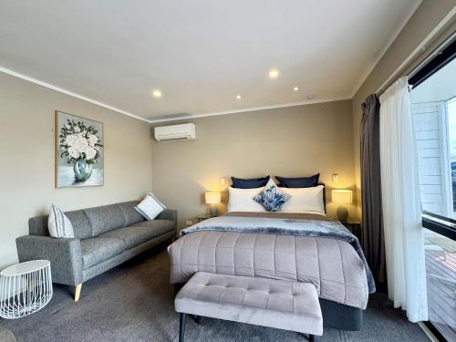 a bedroom with a bed and a couch at Ashbrook Motel Taupo in Taupo