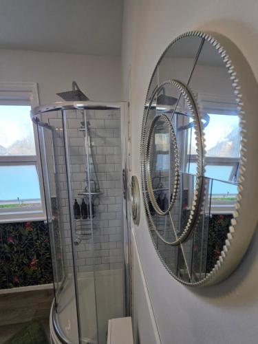a bathroom with a shower and a mirror on the wall at Aura - 8ight Havens in Folkestone