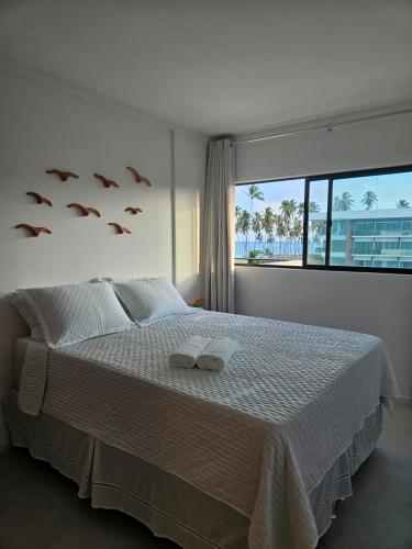 a bedroom with a bed with two slippers on it at Apartamento Ipioca Beach Life in Ipioca