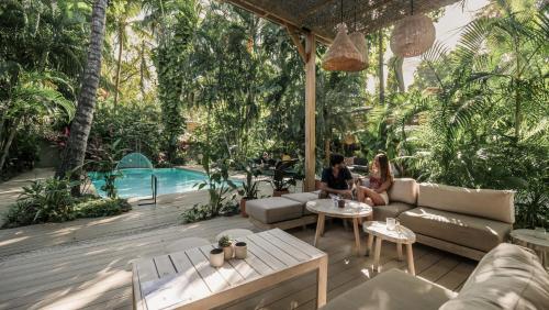 two people sitting on a patio near a swimming pool at Norte Nosara - Steps to Playa Guiones in Nosara
