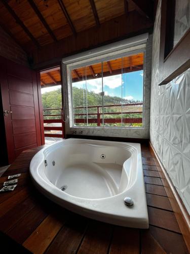a large bath tub in a room with a window at Pousada Varanda Colibri in Monte Verde