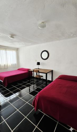 a bedroom with two beds and a table in it at Casa del Parque en Toluca in Toluca