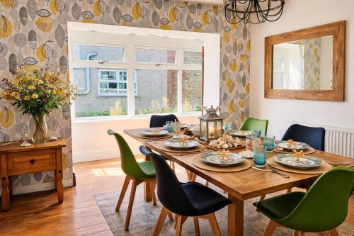 a dining room with a wooden table and green chairs at Old Post Office By The Sea in Allonby