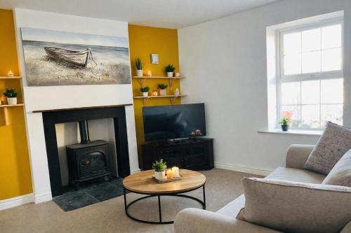a living room with a fireplace and a tv at Old Post Office By The Sea in Allonby