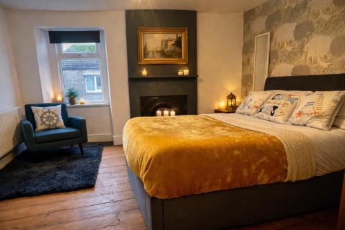 a bedroom with a bed and a chair and a fireplace at Old Post Office By The Sea in Allonby