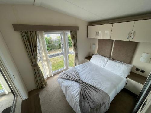 a bedroom with a bed and a large window at Golden Palm Resort - The Ascot - Coastal Caravan Breaks in Chapel Saint Leonards