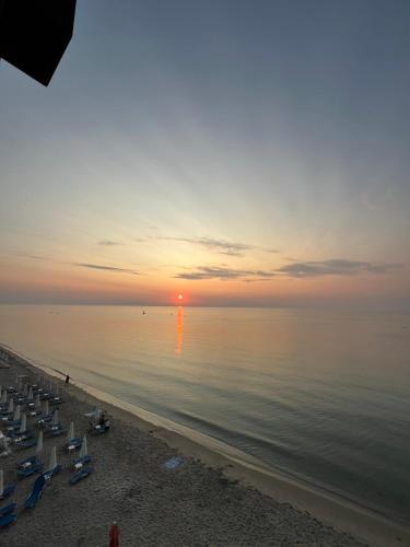 a sunset on a beach with chairs and the ocean at Nefeli HTL in Paralia Katerinis