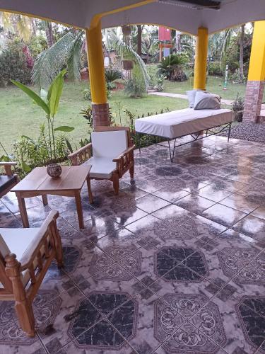 eine Terrasse mit Stühlen, einem Bett und Tischen in der Unterkunft Los Tecales Hostal in Santa Catalina