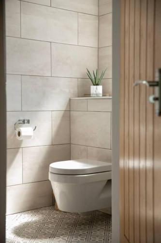a white bathroom with a toilet and a plant at 4 Bed House Sleeps 9 - Parking Garden Bbq Wifi in Yeadon