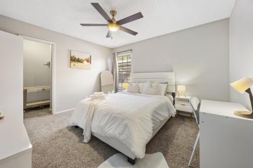 a white bedroom with a bed and a ceiling fan at Emerald Loft - Pool, Gym & Free Parking! in Dallas