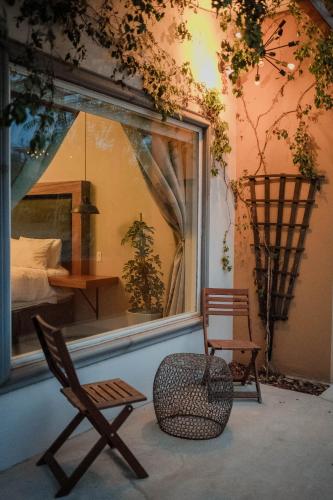 a room with two chairs and a window with a bed at Tierra Mia Hacienda Ruta del Vino in Valle de Guadalupe