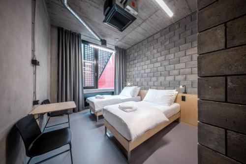 a bedroom with two beds and a desk and a brick wall at Hotel Aréna in Jihlava