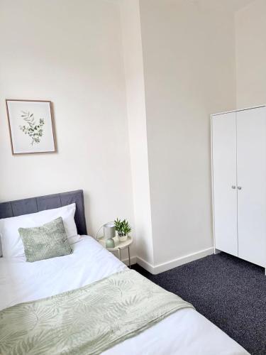 a white bedroom with two beds and a cabinet at Deepdale House - Comfortable 2 Bedroom Home near Major Attractions in Preston in Preston