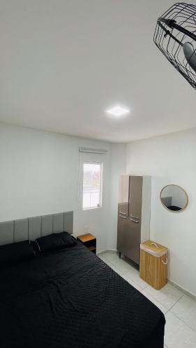 a bedroom with a black bed and a refrigerator at Vitallino Apartment | Modern with A/C, 10 min from the City Center in Caruaru