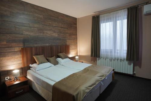 a bedroom with a large bed with a wooden wall at Oak Pearl in Dŭben