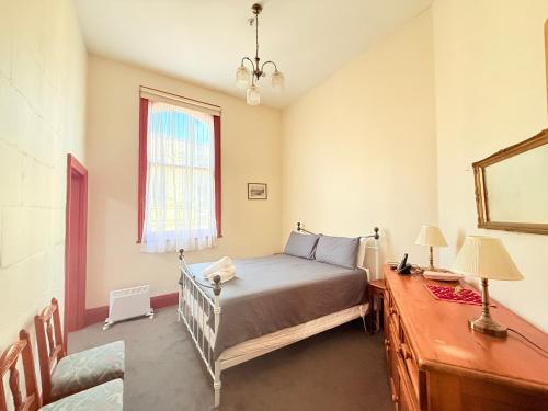 a bedroom with a bed and a mirror and a window at Criterion Boutique Hotel in Oamaru