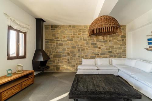 a living room with a white couch and a brick wall at Lindos 4 me Villa in Lindos