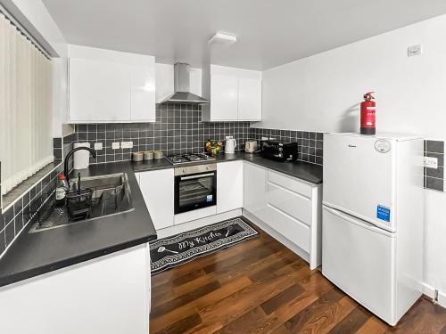 a kitchen with white appliances and a wooden floor at New Manchester City Getaway House with 2 FREE Parking in Manchester