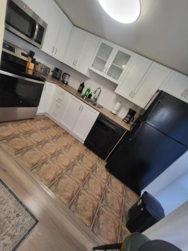 a kitchen with white cabinets and black appliances at Small Apartment for 2 in St. Catharines