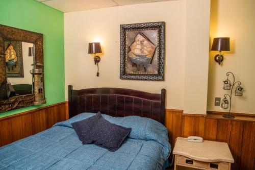 a bedroom with a blue bed and a picture on the wall at Hotel La Castellana in Santiago