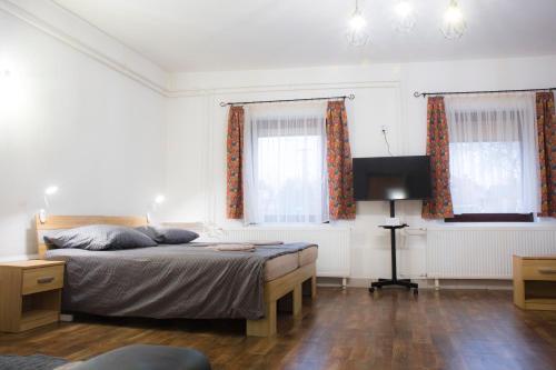a bedroom with a bed and a desk and two windows at Bázis Vendégház Hajdúnánás in Hajdúnánás