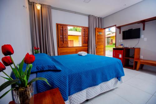 a bedroom with a blue bed with a vase of red roses at Pousada Sítio Machado in Viçosa do Ceará