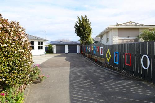 a fence with paintings on it next to a house at Rev it up Homestay in Feilding