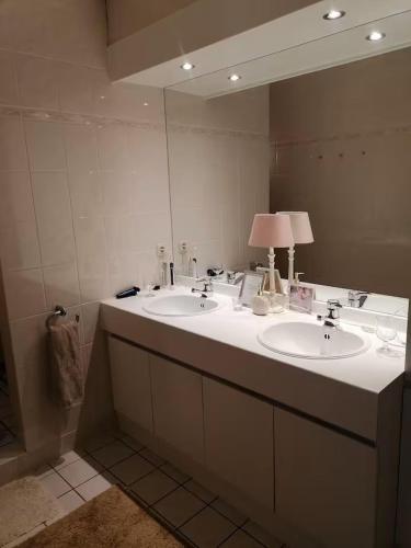 a bathroom with two sinks and a large mirror at logies Huis Liselotte in Genk