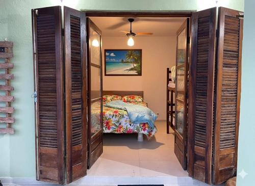 a bedroom with a bed in a room with wooden doors at Pousada NASCER DO SOL in Bertioga
