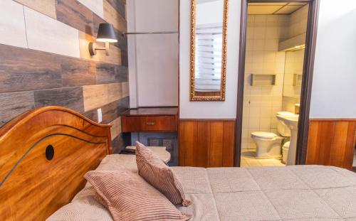 a bedroom with a bed and a bathroom with a toilet at Hotel La Castellana in Santiago