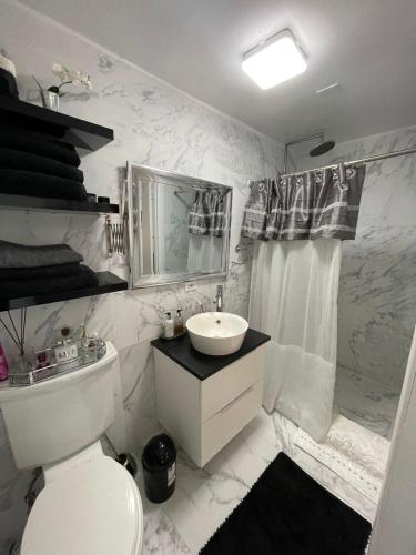 a white bathroom with a sink and a toilet at Modern Ocean View Apartment in Upper Prince's Quarter