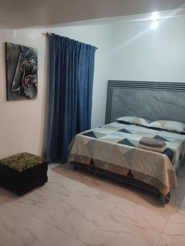 a bedroom with a bed and a blue curtain at El Hogar de Ami in Cali