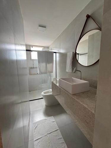 a bathroom with a sink and a toilet and a mirror at Flat com vista mar in Mucuri