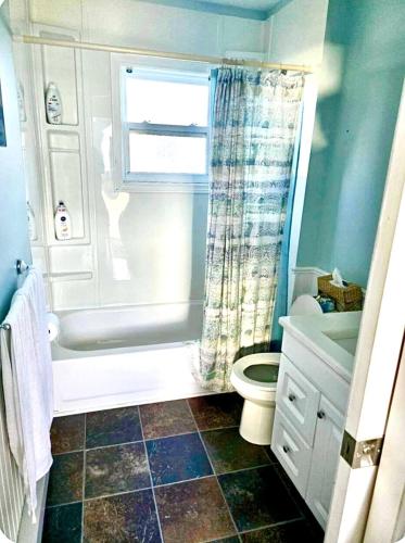 a bathroom with a tub and a toilet and a window at Seaside Cottage 180 Views in Petit-Etang