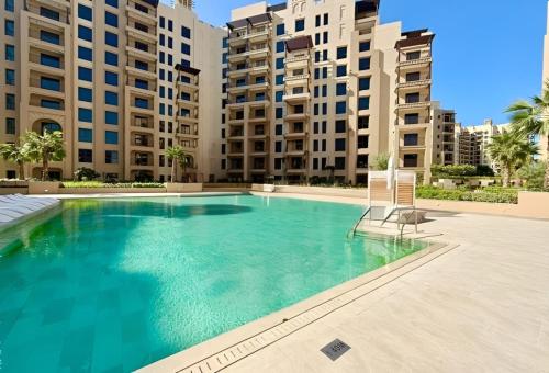 a swimming pool with a chair and some buildings at HAVN - 1 bedroom in Madinat Jumeirah Living in Dubai