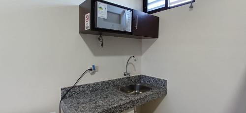 a bathroom with a sink and a tv on the wall at Suites del Pacífico in Salinas